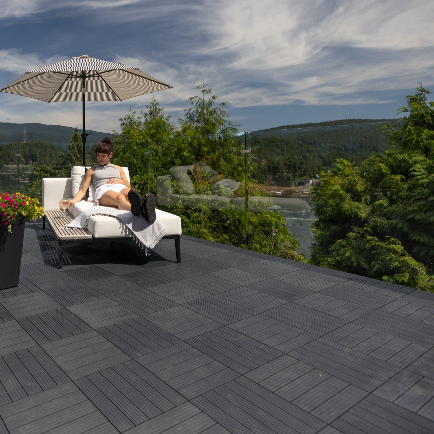 Person sitting on a patio with a scenic view of mountains and water.