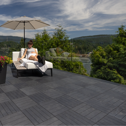 Person sitting on a patio with a scenic view of mountains and water.